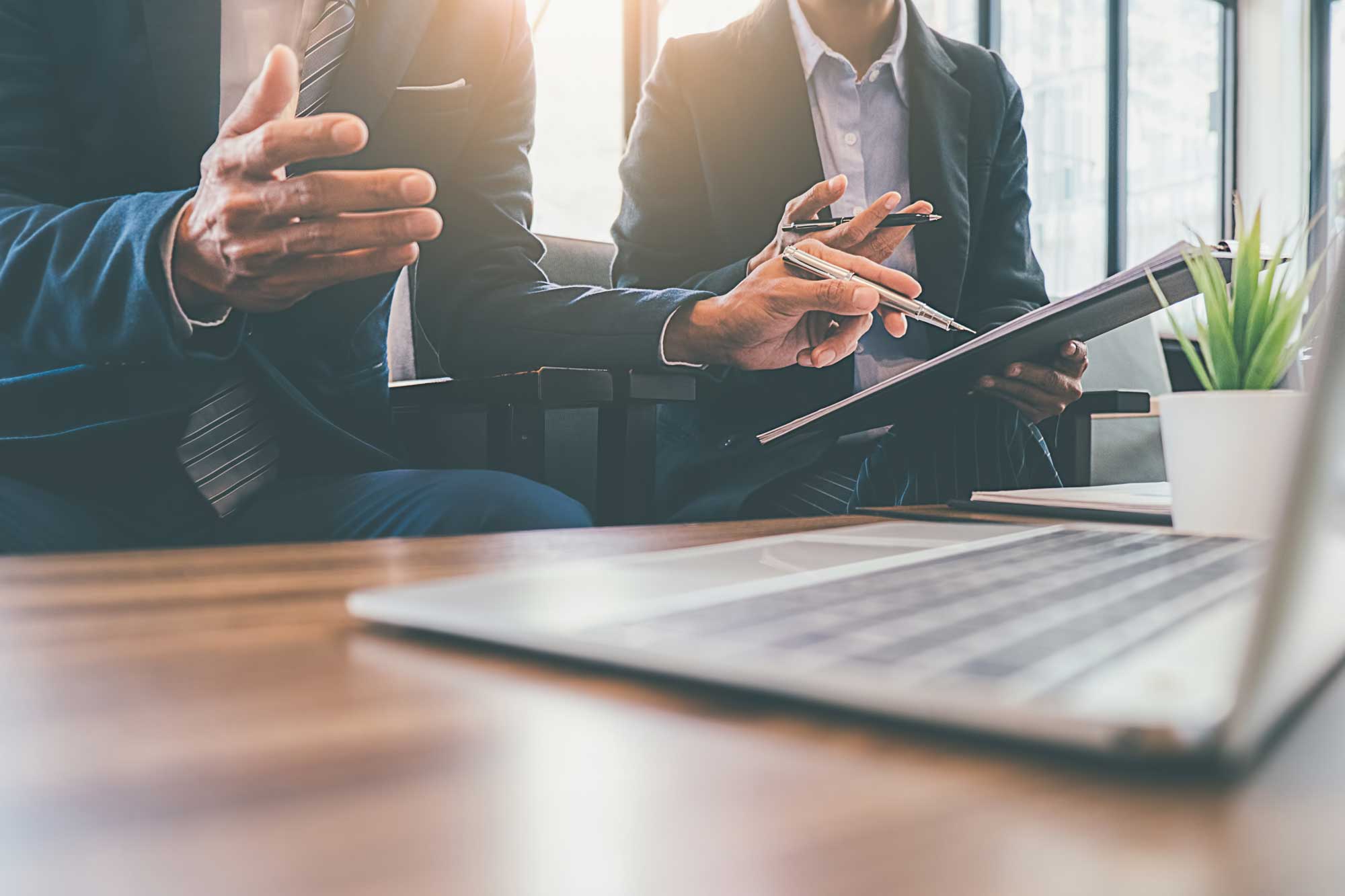 Two businessmen are pointing to the company cost graph and then analyzing together